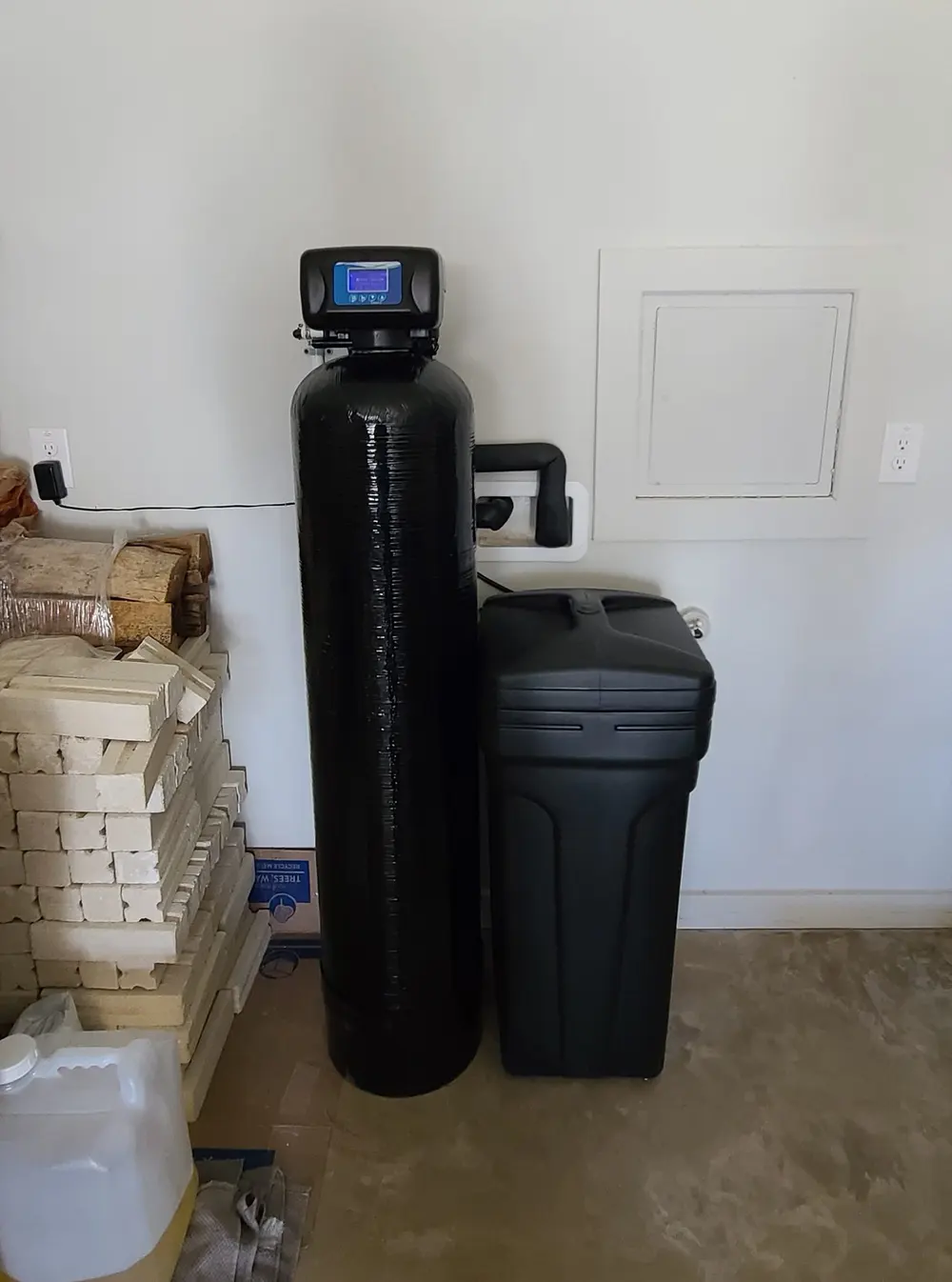 Softener and brine tank installed in a garage during ongoing construction
